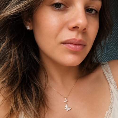 Woman wearing a 925 sterling silver butterfly necklace with mother of pearl and matching stud earrings